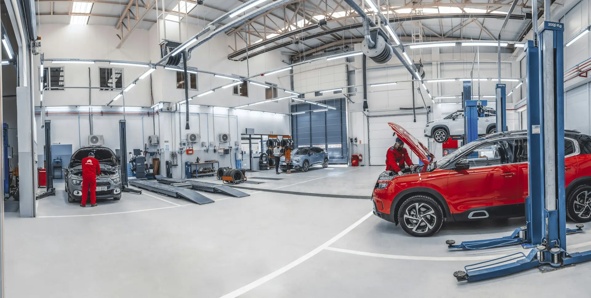 A bright, spacious workshop with cars on lifts and technicians at work