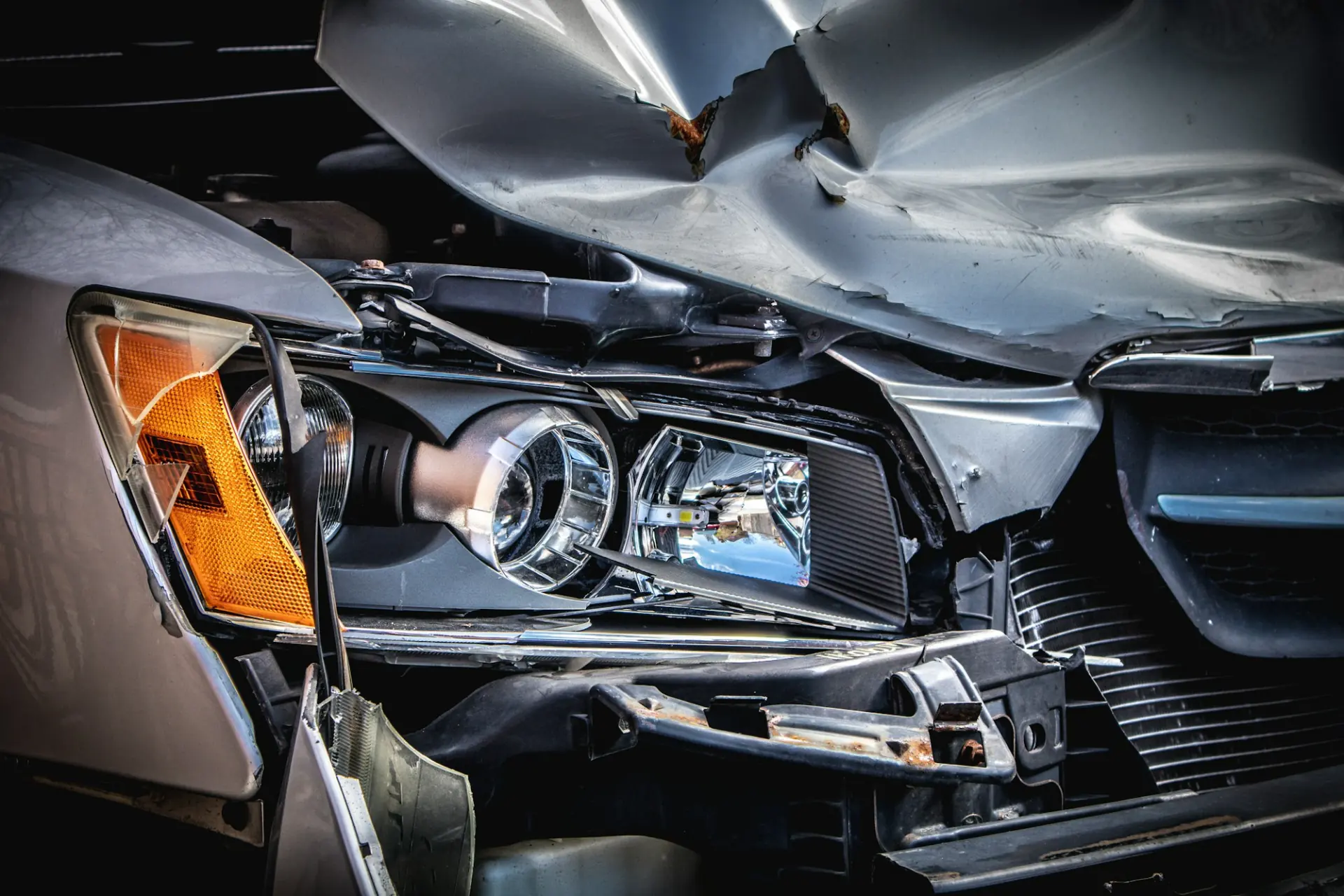 Close-up of a car's crumpled bonnet and broken headlight after a collision
